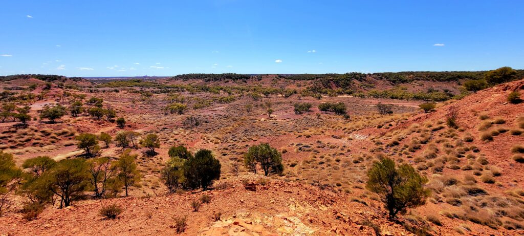 Deep red earth and spinifex grass of the Australian outback in Winton, Queensland, representing the grounding energy of the Muladhara Root Chakra.