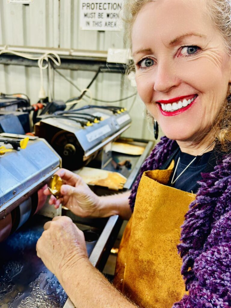 Sarah Hope smiling while polishing a stone a lapidary wheel, demonstrating personal transformation.
