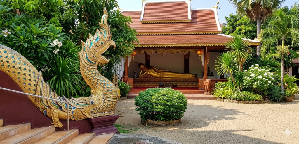 Golden Makara Sea Dragon statue guarding the entrance to a temple with a reclining Buddha in the background.