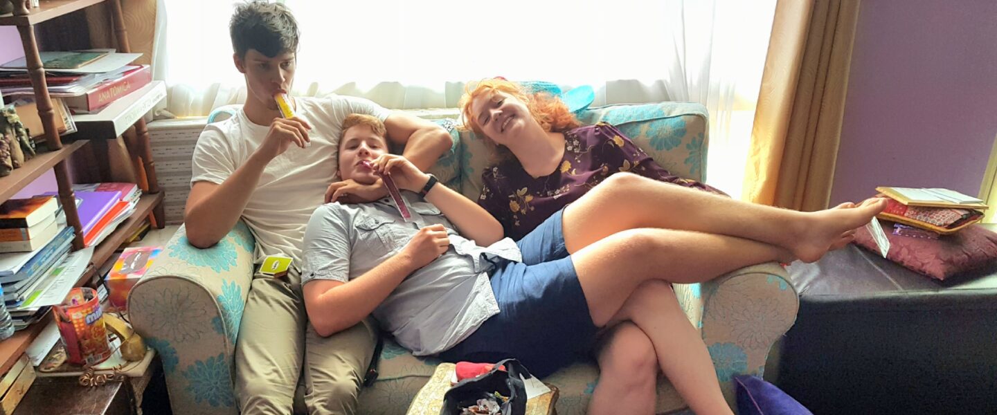 Three siblings sitting together on a couch, representing the love and connection within the Hrit Chakra.